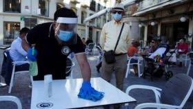 Un camarero limpia la mesa antes de servir al cliente.
