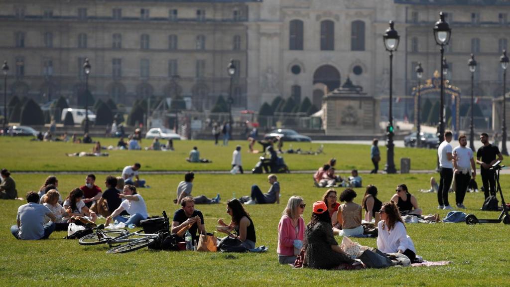 Decenas de personas disfrutan del buen tiempo cerca de Los Inválidos, en París.