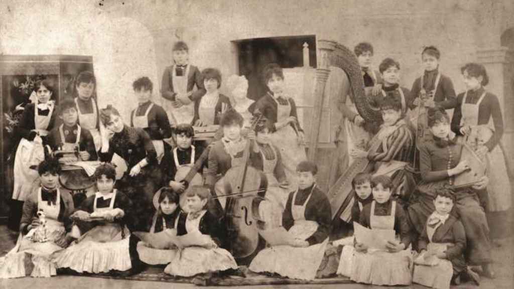 Clotilde Cerdà, con la cabeza apoyada sobre su mano, rodeada de las alumnas de la Academia de Ciencias, Artes y Oficios para la Mujer que fundó en 1885.