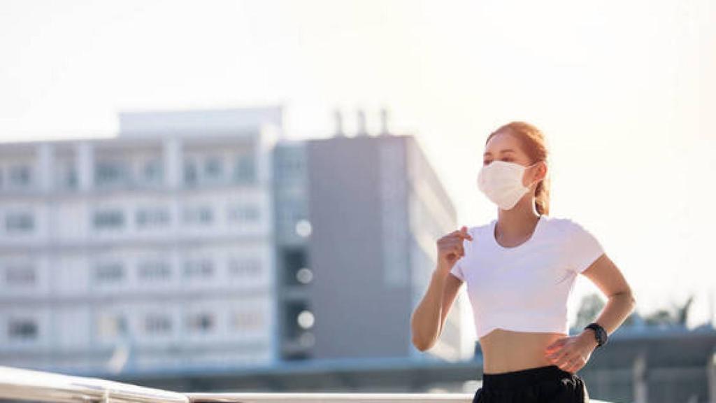 Una joven con una mascarilla mientras hace running.