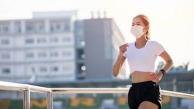 Una joven con una mascarilla mientras hace running.