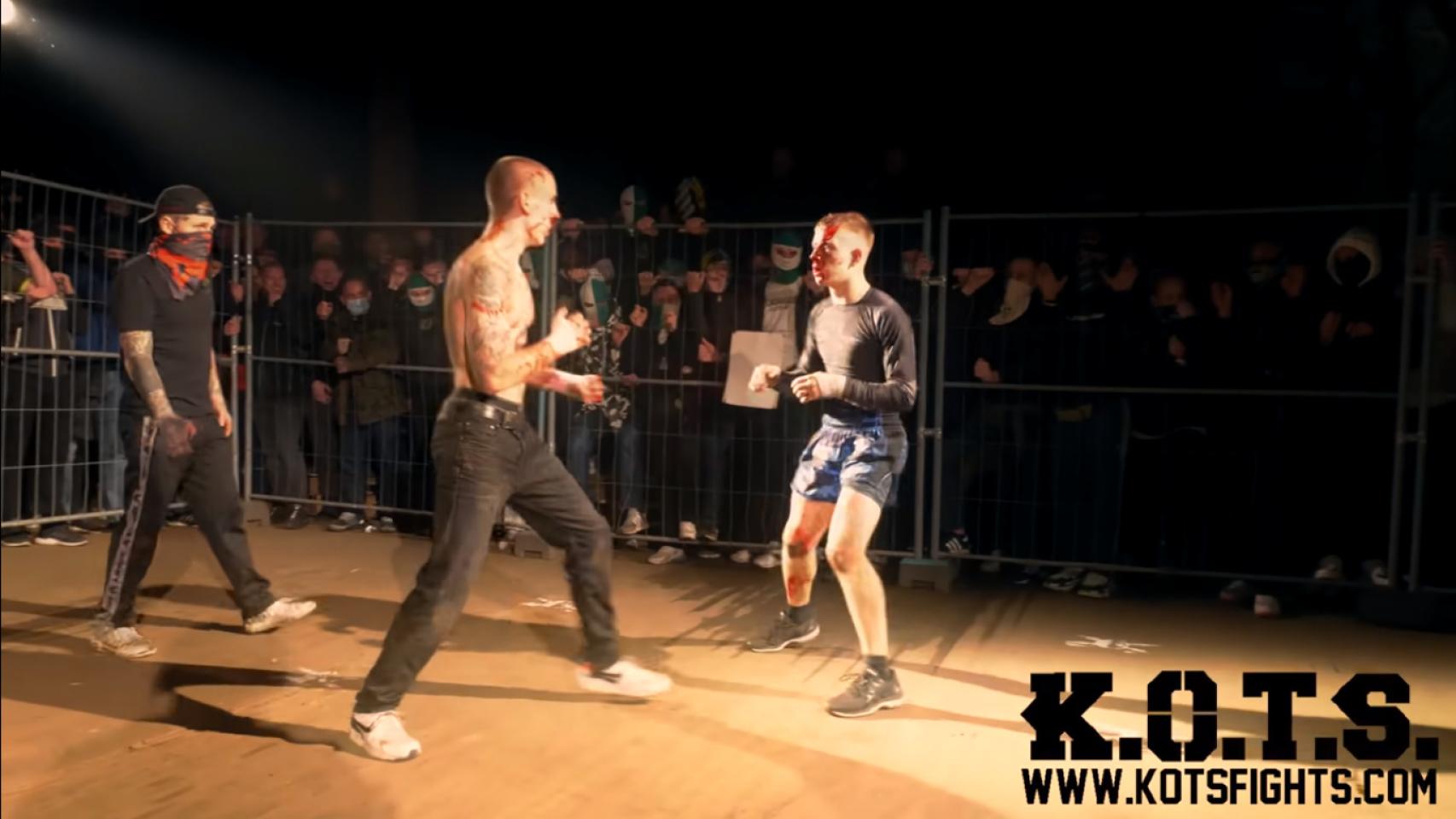 Un hombre en un ring de boxeo con un hombre con un pantalón corto blanco y  una camiseta que dice boxer.