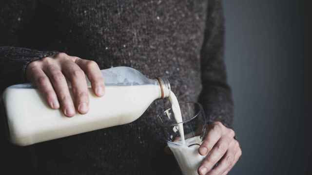 Un hombre sirve un vaso de leche.
