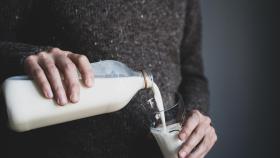 Un hombre sirve un vaso de leche.