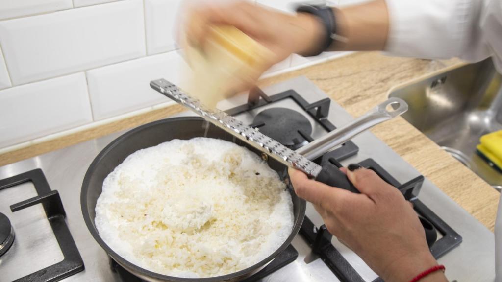 La chef Bárbara, antes de añadir las espinacas trituradas, ralla queso parmigiano en el risotto.