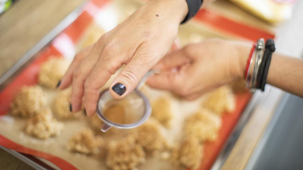 Bárbara espolvorea, con un pequeño colador, la canela molida sobre las galletas de arroz recién hechas.