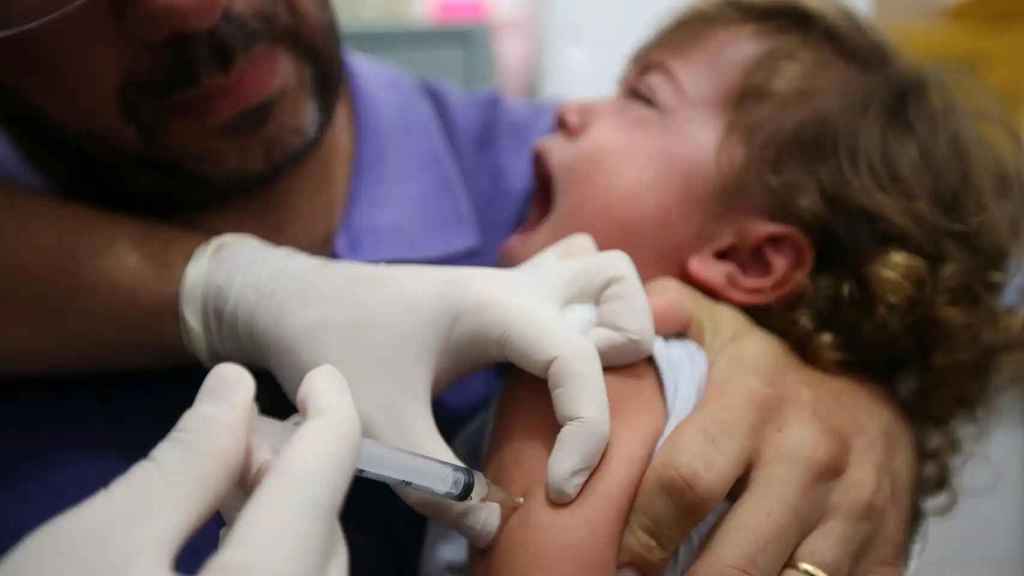 Un sanitario vacuna a un niño.