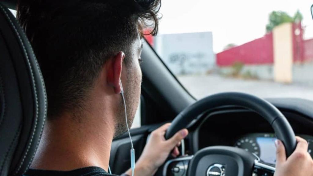 Un conductor con auriculares mientras conduce.