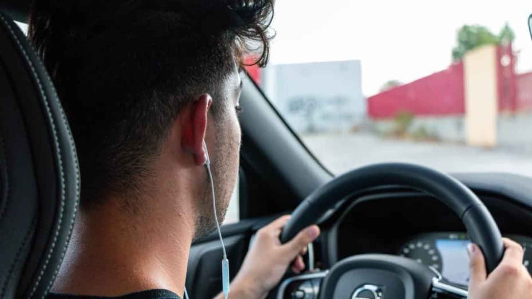 Un conductor con auriculares mientras conduce.