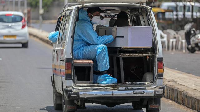 Un trabajador sanitario en una furgoneta que transporta un fallecido en Ahmedabad, India.