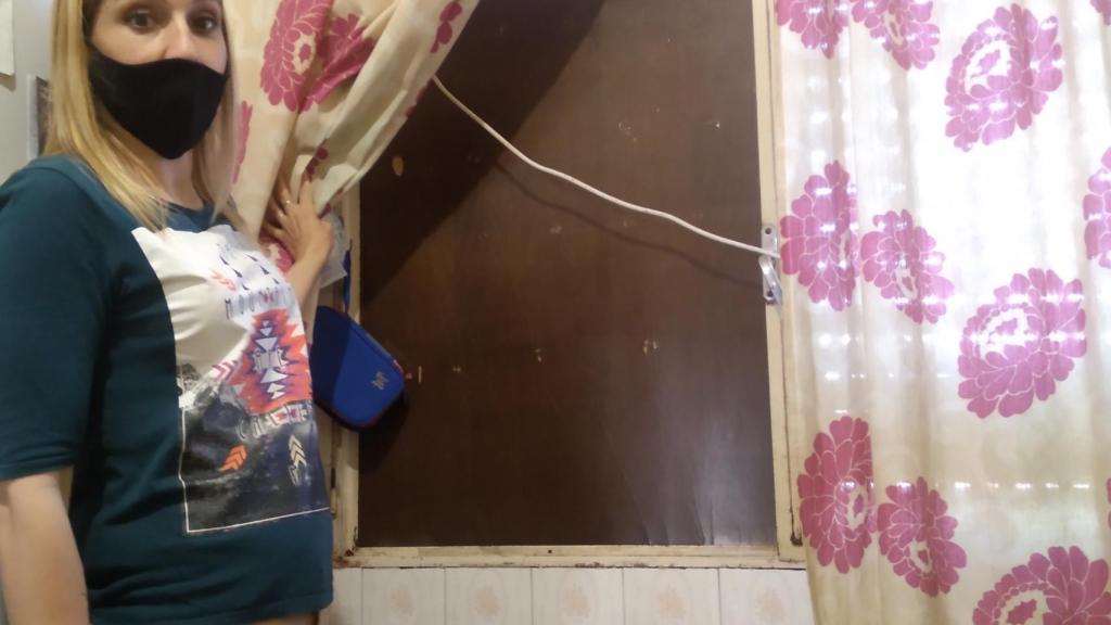 Jéssica mostrando una ventana cerrada con una lámina de madera de la casa que le cedieron tras los terremotos.
