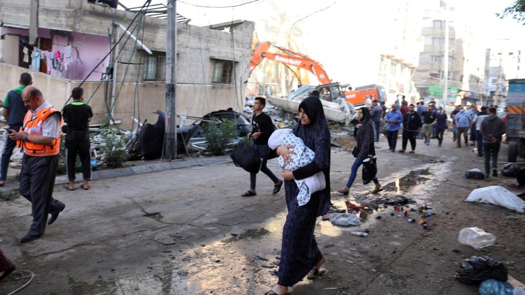 Una mujer lleva a su bebé durante los rescates en Gaza.