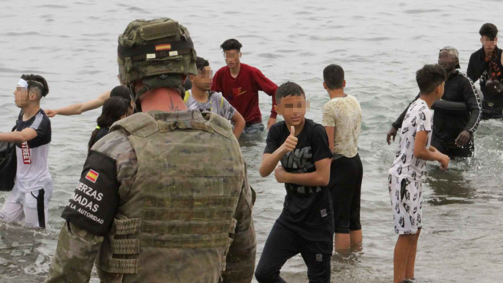 Un militar observa a un grupo de menores marroquíes en las playas de Ceuta.