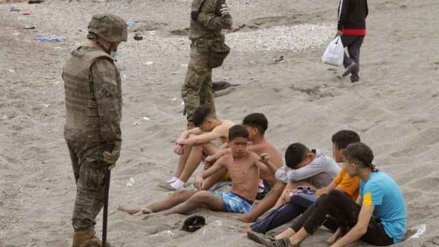 Miembros del Ejército de Tierra junto a un grupo de inmigrantes menores que han llegado a Ceuta. Efe