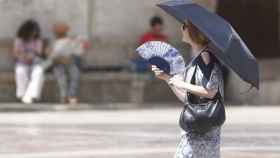 Una mujer se abanica y se protege del sol con un paraguas en Valencia.
