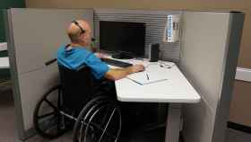 Una persona con movilidad reducida, frente a una pantalla de ordenador en su puesto de trabajo. FOTO: Pixabay.