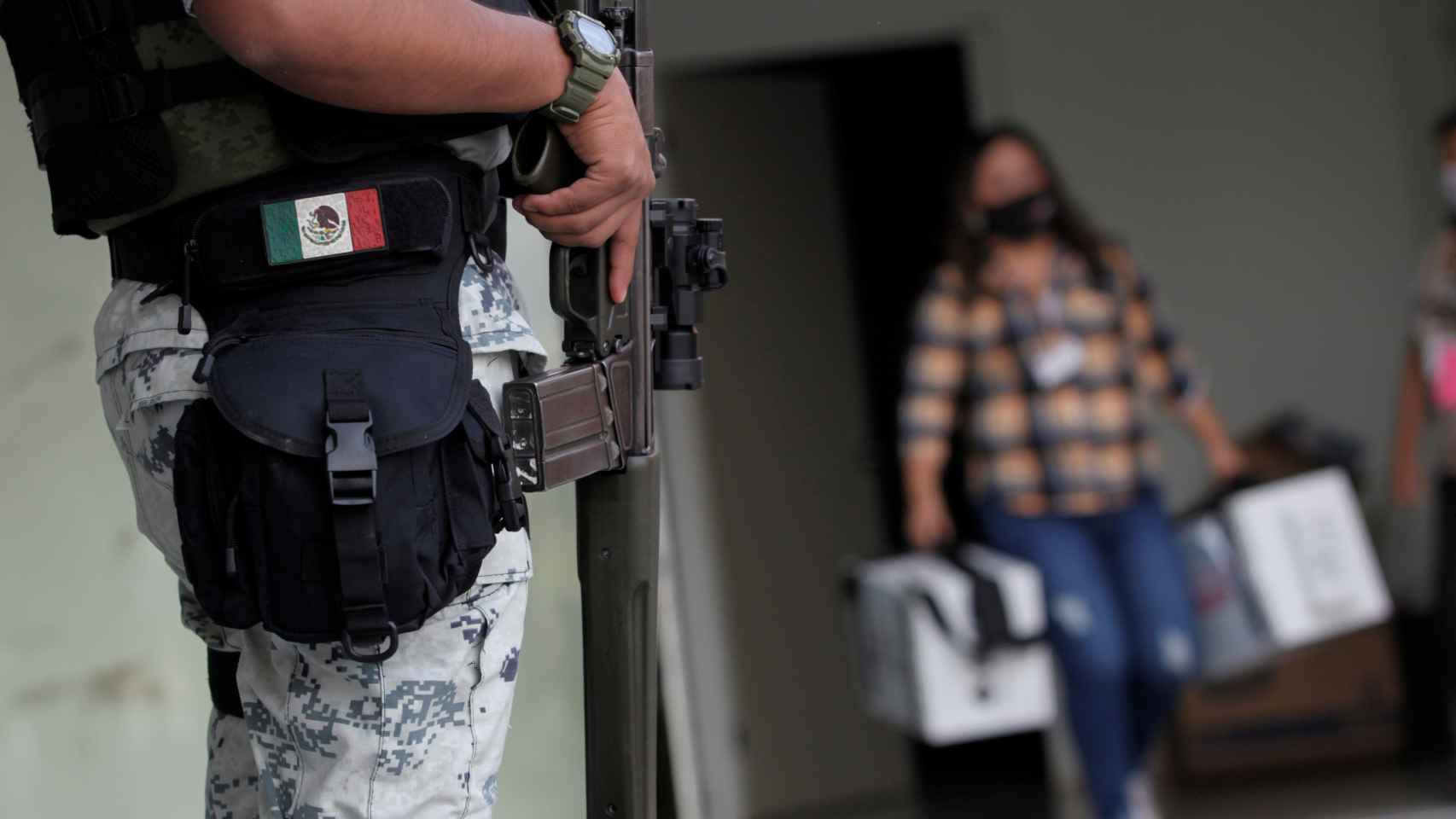 Un agente de la Guardia Nacional escolta a una mujer con urnas en el Estado de Nuevo León.