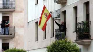 Un ciudadano ondea la bandera española desde su ventana.
