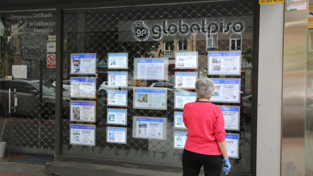 Una mujer echa un vistazo a las ofertas de una agencia inmobiliaria.