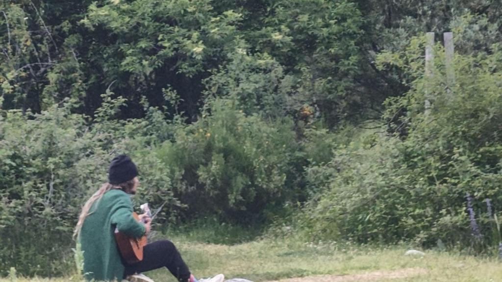 Un hermano de la Familia Arcoíris toca la guitarra en el campamento.