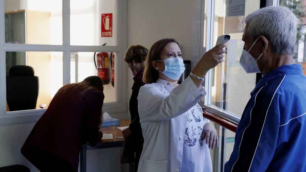 Una trabajadora toma la temperatura a un usuario a las puertas de un centro de mayores en Madrid.