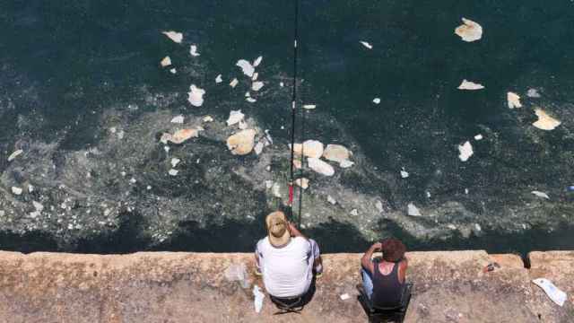 Dos personas pescan en aguas contaminadas.