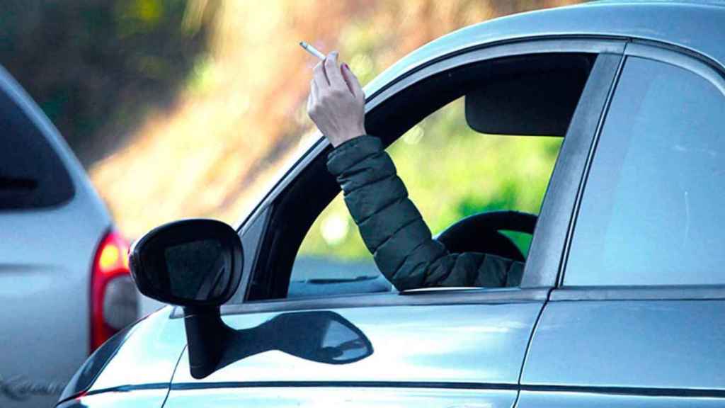 Una persona fumando mientras conduce.