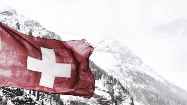 La bandera de Suiza con las montañas nevadas al fondo.