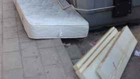 Un colchón tirado junto a un contenedor en una calle de Alicante.
