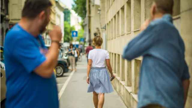 Una mujer es acosada por dos hombres mientras camina por la calle.