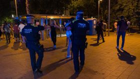 Dos agentes desalojan una calle de Barcelona por el nuevo toque de queda.