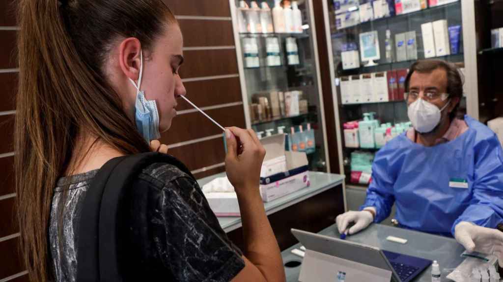 Una joven se hace un test de antígeno en una farmacia.
