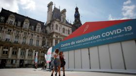 Dos mujeres caminan delante de un centro de vacunación en París.