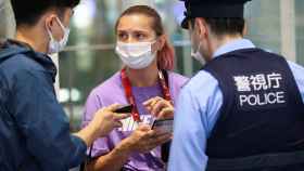 Belarusian athlete Krystsina Tsimanouskaya talks with a police officer at Haneda international airport in Tokyo, Japan