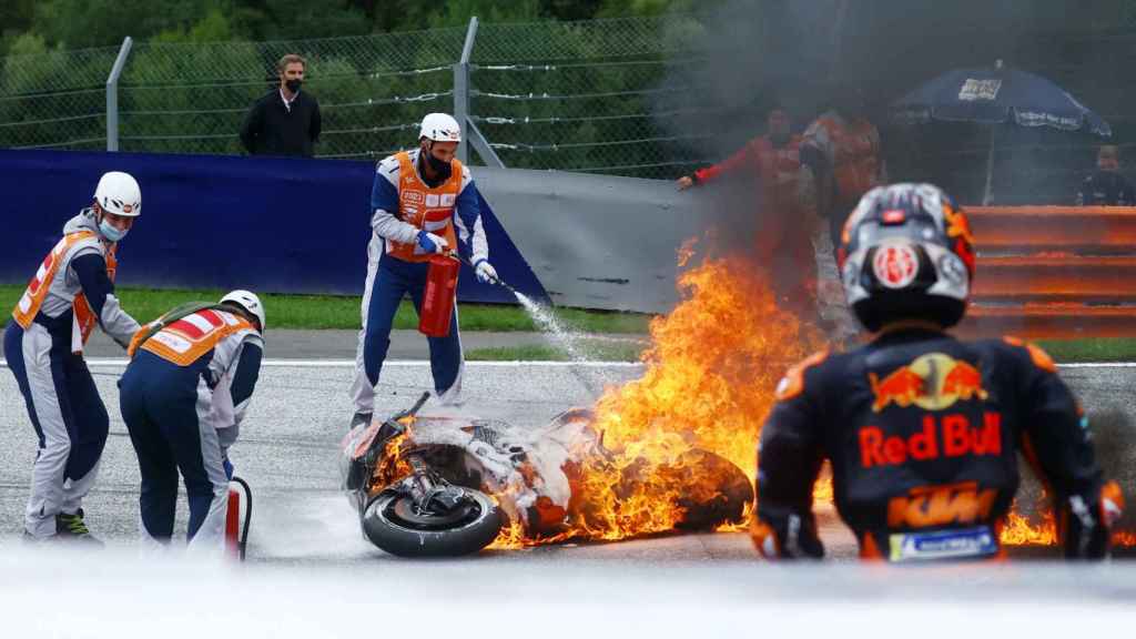Dani Pedrosa observa como las llamas de su KTM son apagadas por los comisarios de pista, en el Red Bull Ring de Spielberg.