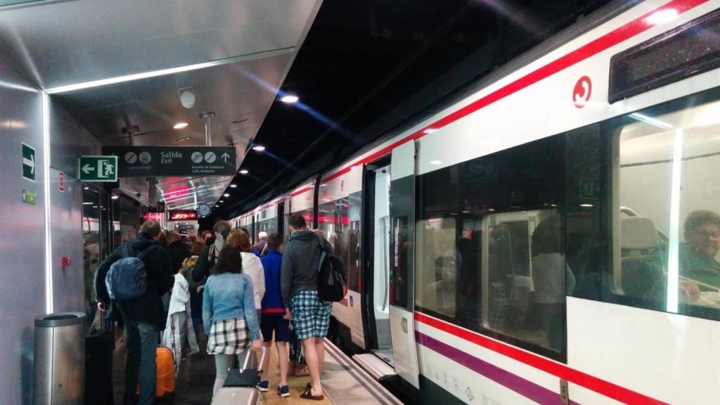 Imagen de varios pasajeros junto a un tren de Cercanías, en Málaga.