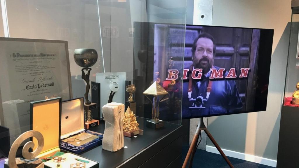 Bud Spencer proyectado en una televisión junto a una vitrina con sus efectos personales.