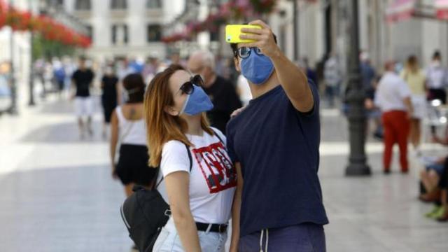 Una pareja se hace una foto con la mascarilla puesta.