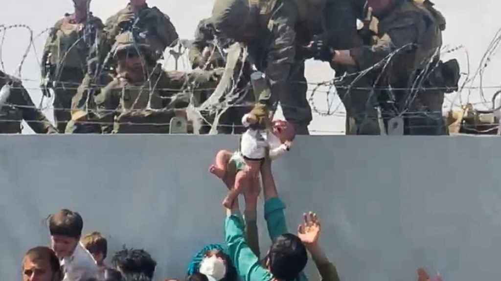 Los afganos entregan a sus niños a los soldados de EEUU para que los pongan a salvo en un vuelo.