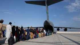 Decenas de afganos hacen cola para embarcar en un avión estadounidense, en la pista del aeropuerto de Kabul.