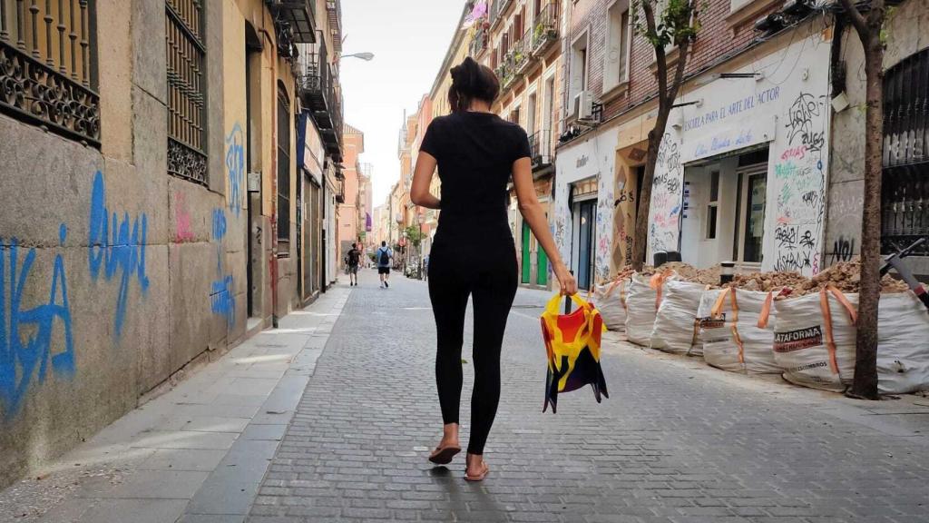 A neighbor from Malasaña walks with a bag with the rainbow flag.