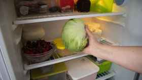 Una persona guarda una lechuga iceberg en el frigorífico.