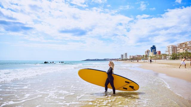 Una surfista en la playa de San Juan de Alicante.