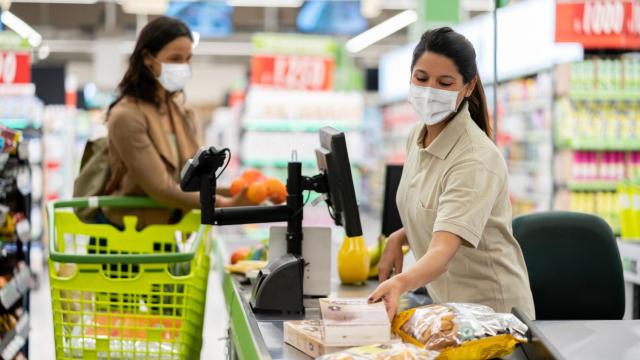 Una cajera pasando distintos alimentos por la cinta.