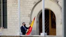 Un ujier se lleva la bandera española de la Galería Gótica del Palau de la Generalitat tras la comparecencia de Pedro Sánchez.