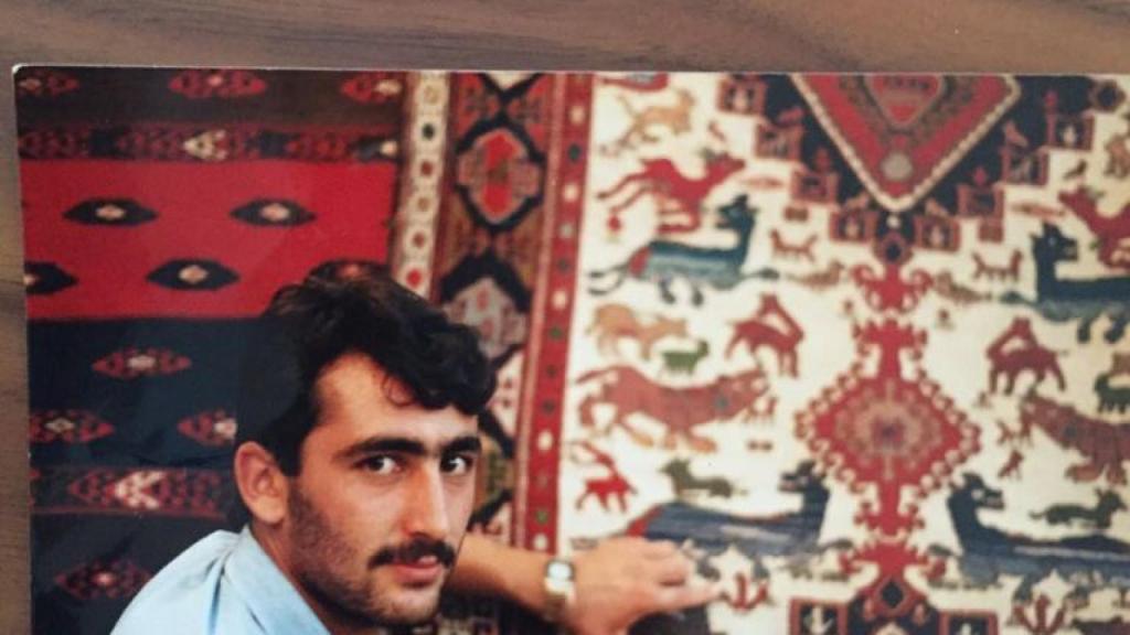 Nurettin poses in front of some rugs, a product with which he began trading.