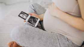 Una mujer embarazada mira las ecografías del bebé.