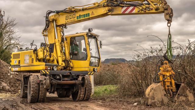 Un trabajador utiliza una excavadora en el sector agrario.