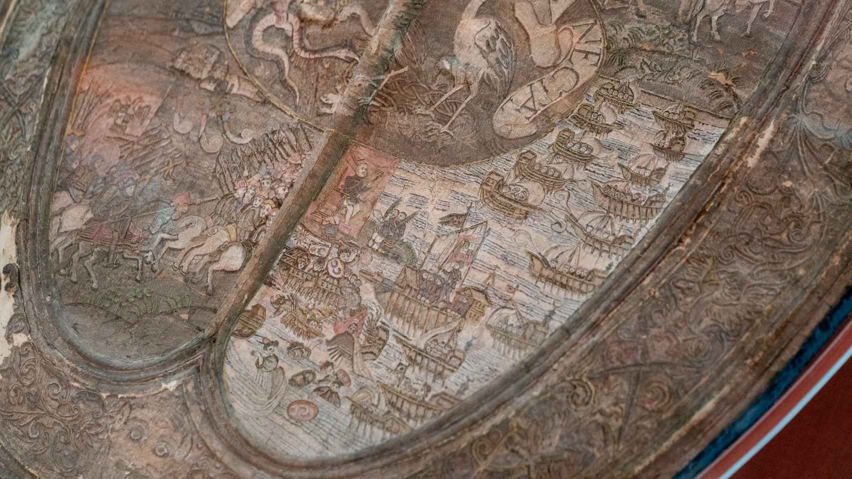 Detalle de la adarga. La escena de la derecha es la representación de la batalla de Lepanto. En ella aparecen Felipe II, Juan de Austria y Alí Pachá.