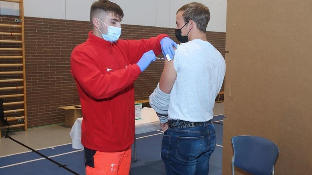 Un sanitario vacuna a un joven